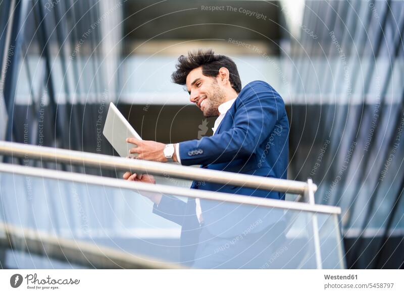 Smiling businessman using tablet on balcony of an office building Occupation Work job jobs profession professional occupation business life business world