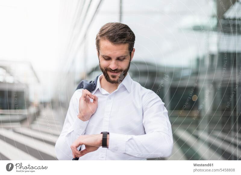 Smiling young businessman checking the time Businessman Business man Businessmen Business men Time portrait portraits smiling smile wrist watch Wristwatch