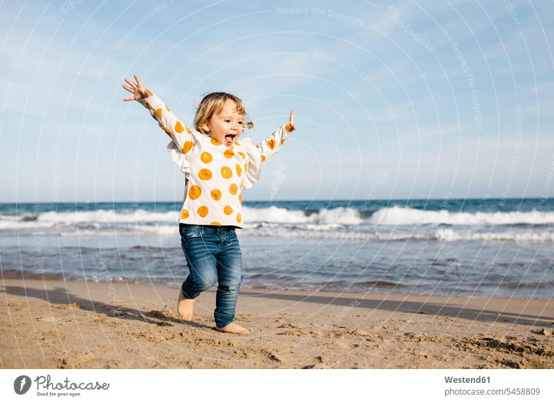 Happy little girl running barefoot on the beach Vitality Verve vigour vigorous seafront seashore Oceanside Sea Shore exhilaration elation cheerful carefree Fun