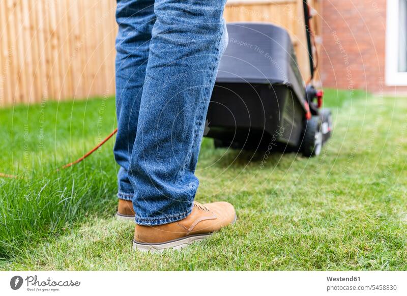Man standing with lawn mower at backyard color image colour image outdoors location shots outdoor shot outdoor shots day daylight shot daylight shots day shots