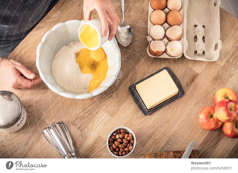 Woman hand putting egg yolk in bowl while standing at kitchen island color image colour image indoors indoor shot indoor shots interior interior view Interiors