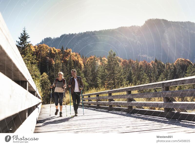 Austria, Alps, Couple crossing bridge walking with hiking poles caucasian caucasian appearance caucasian ethnicity european White - Caucasian mature men