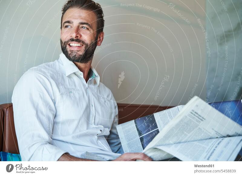 Portrait of happy businessman wearing white shirt sitting on couch with newspaper business life business world business person businesspeople Business man