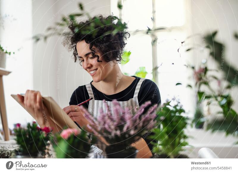 Smiling young woman with clipboard in a small shop with plants Occupation Work job jobs profession professional occupation human human being human beings humans