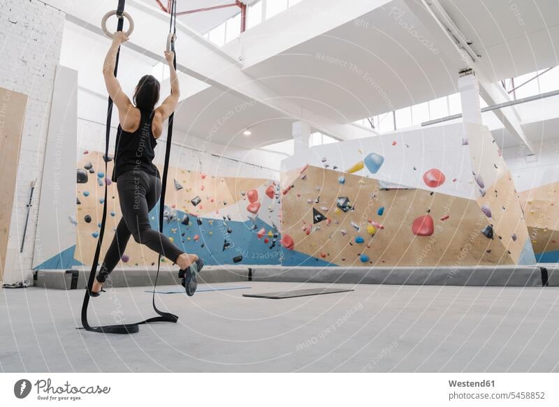 Woman doing stretching exercises on gymanstic rings before climbing on the rock wall (value=0) human human being human beings humans person persons