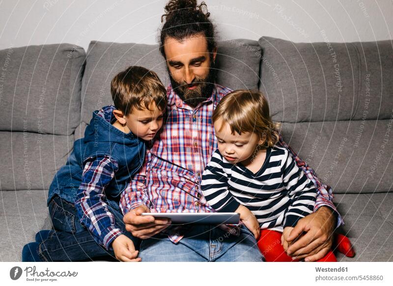 Father sitting on the couch with his children watching movies on digital tablet father pa fathers daddy papa digitizer Tablet Computer Tablet PC