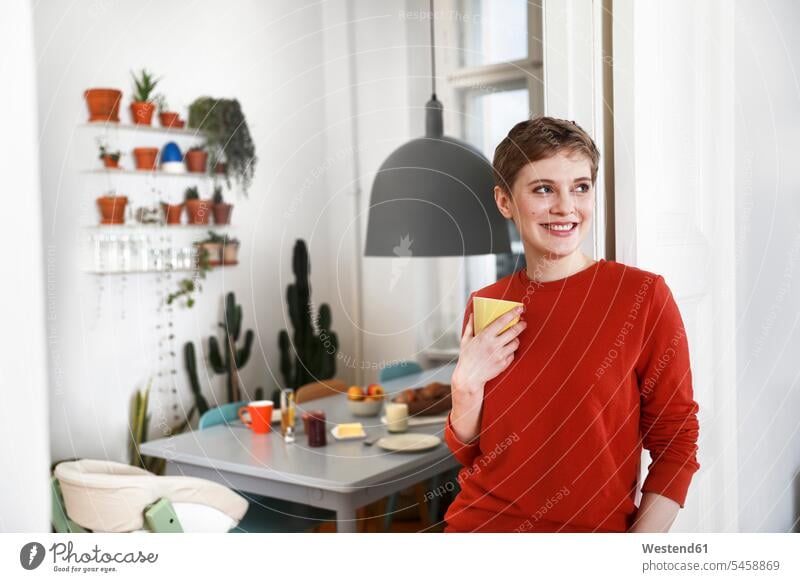 Woman standing in her comfortable home, drinking coffee Coffee happiness happy amenities amenity at home woman females women Drink beverages Drinks Beverage