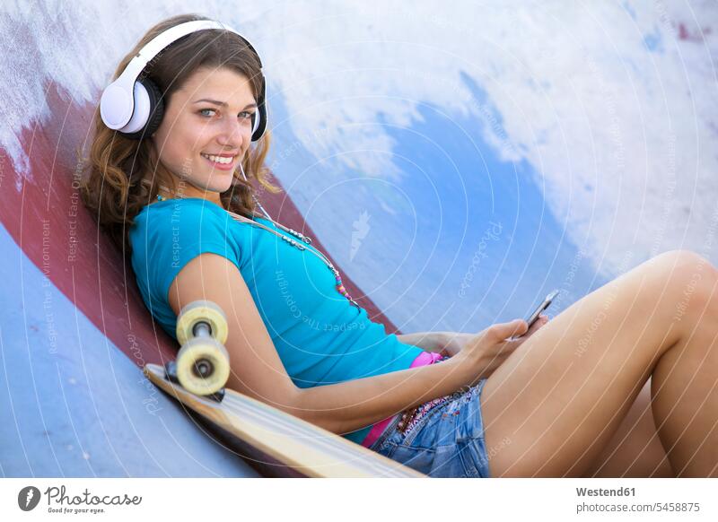 Female longboarder with earphones lying in halfpipe Longboard music laying down lie lying down woman females women headphones headset hearing Half Pipe