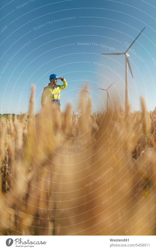 Engineer standing in a field at a wind farm Field Fields farmland engineer engineers wind park engineering engineering science technology technologies