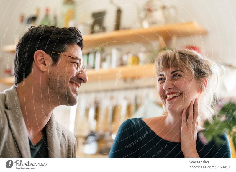 Happy couple smiling at each other in kitchen at home Eye Glasses Eyeglasses specs spectacles smile delight enjoyment Pleasant pleasure Cheerfulness