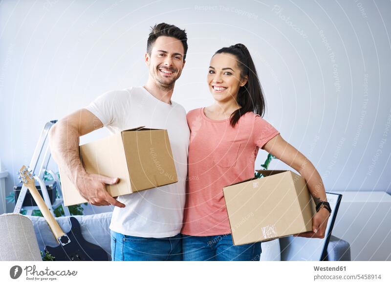 Portrait of happy couple moving in happiness portrait portraits twosomes partnership couples cardboard box cardboard boxes packing case packing cases move in