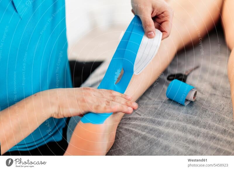 Visually impaired physiotherapist applying Kinesio tape on boy's hand in clinic color image colour image indoors indoor shot indoor shots interior interior view