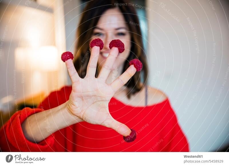Mature woman standing in kitchen , with rasperries on her fingers Take five Eat five red Showing show pullover sweater jumper Sweaters Raspberry Raspberries