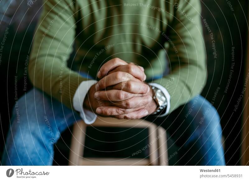 Man with hands clasped sitting on table at home color image colour image indoors indoor shot indoor shots interior interior view Interiors day daylight shot