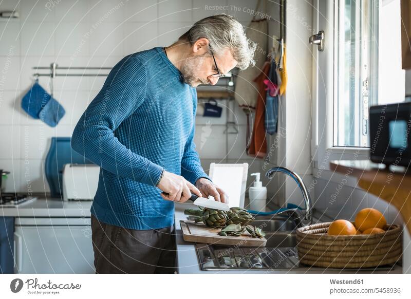 Mature man preparing artichokes in his kitchen human human being human beings humans person persons celibate celibates singles solitary people solitary person