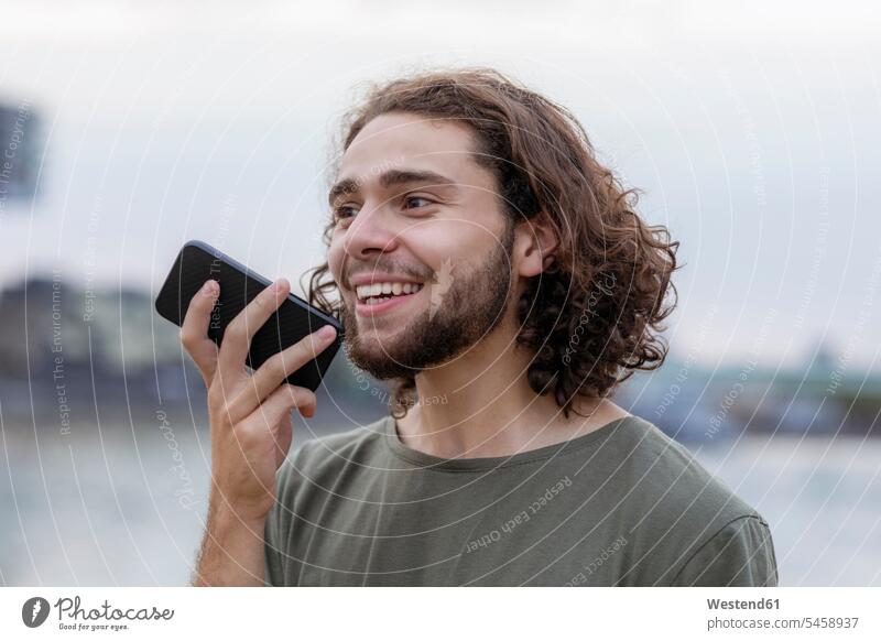 Portrait of happy young man using smartphone outdoors Smartphone iPhone Smartphones portrait portraits smiling smile happiness mobile phone mobiles