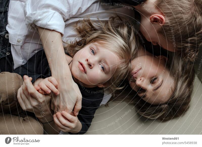 Directly above view of blond boy lying with brother and mother on sofa at home color image colour image indoors indoor shot indoor shots interior interior view