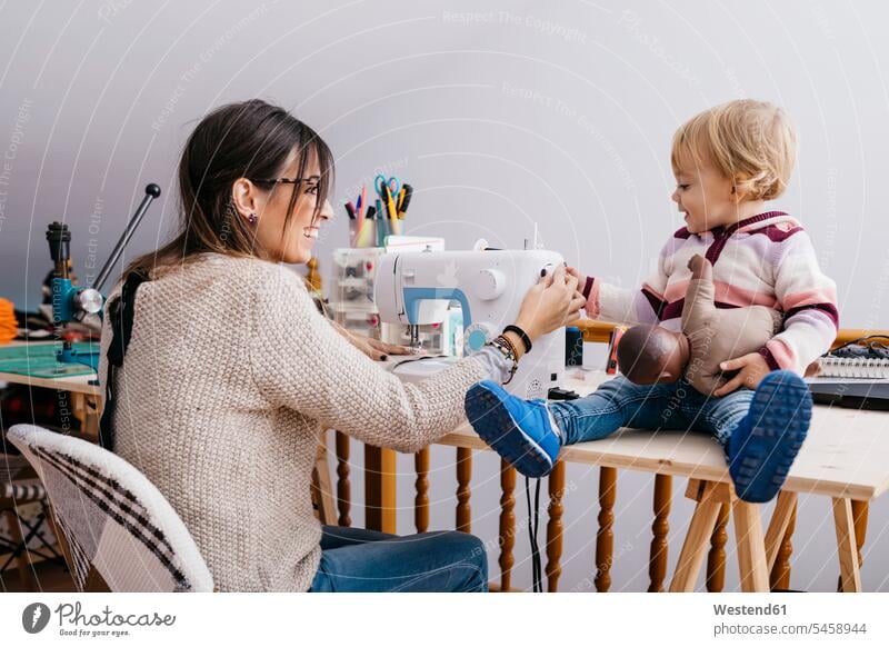 Happy mother with little daughter at home using sewing machine happiness happy mommy mothers mummy mama sewing machines daughters parents family families people
