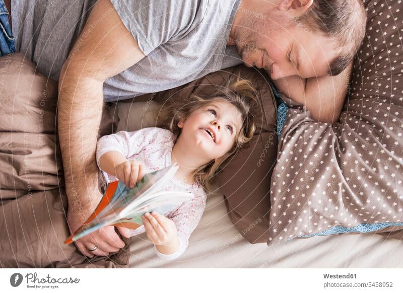 Father and daughter reading a book in bed books Bed - Furniture beds relax relaxing relaxation happy closeness propinquity Contented Emotion pleased laying down