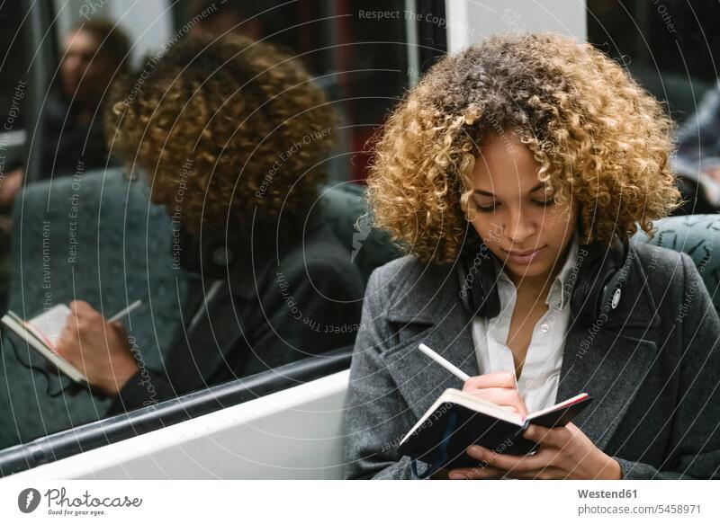 Woman taking notes on a subway business life business world business person businesspeople business woman business women businesswomen windows diaries pencil