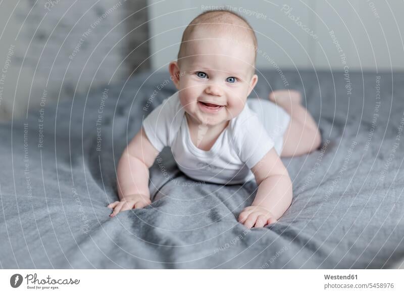Portrait of laughing baby boy lying on bed portrait portraits baby boys male Laughter beds laying down lie lying down babies infants people persons human being
