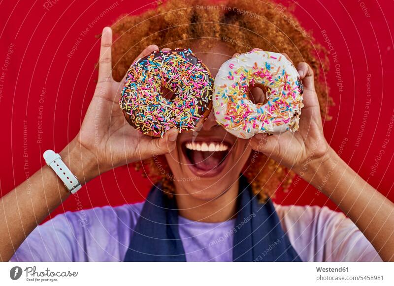 Playful woman holding two donuts in front of her eyes human human being human beings humans person persons African black black ethnicity coloured adult grown-up