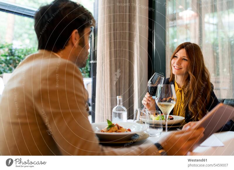 Smiling woman with glass of red wine looking at man in a restaurant smiling smile drinking eyeing couple twosomes partnership couples Red Wine Red Wines