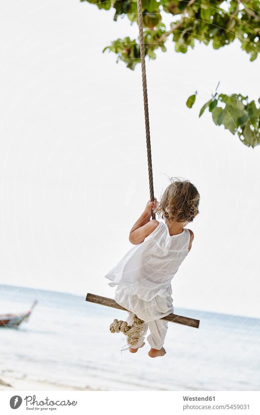 Thailand, Phi Phi Islands, Ko Phi Phi, little girl on a rope swing on the beach swing set playground swing swingset females girls swinging rock rocking beaches