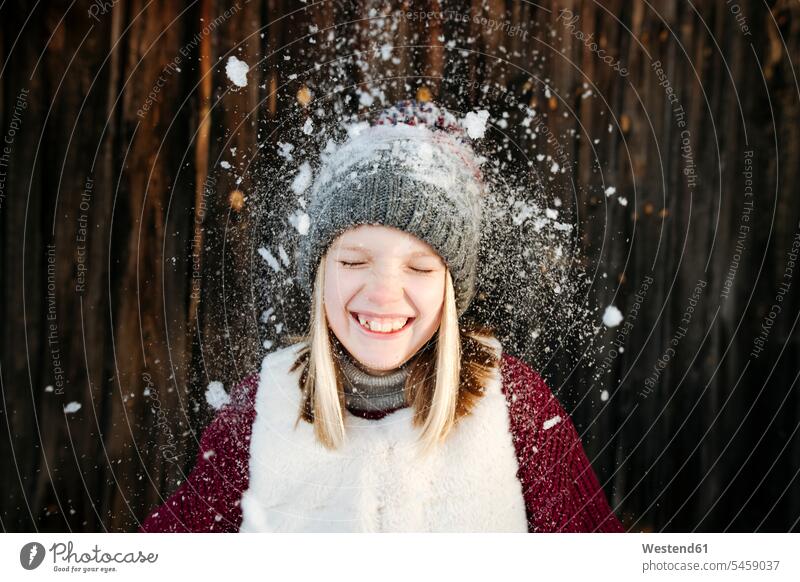 Snow falling on happy girl wearing woolly hat caps hats smile seasons hibernal delight enjoyment Pleasant pleasure Cheerfulness exhilaration gaiety gay glad