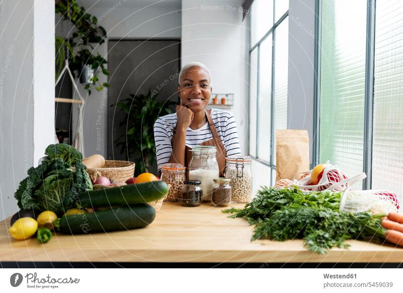 Woman with apron in kitchen , unpacking freshly bought organic fruit and vegetables human human being human beings humans person persons African black