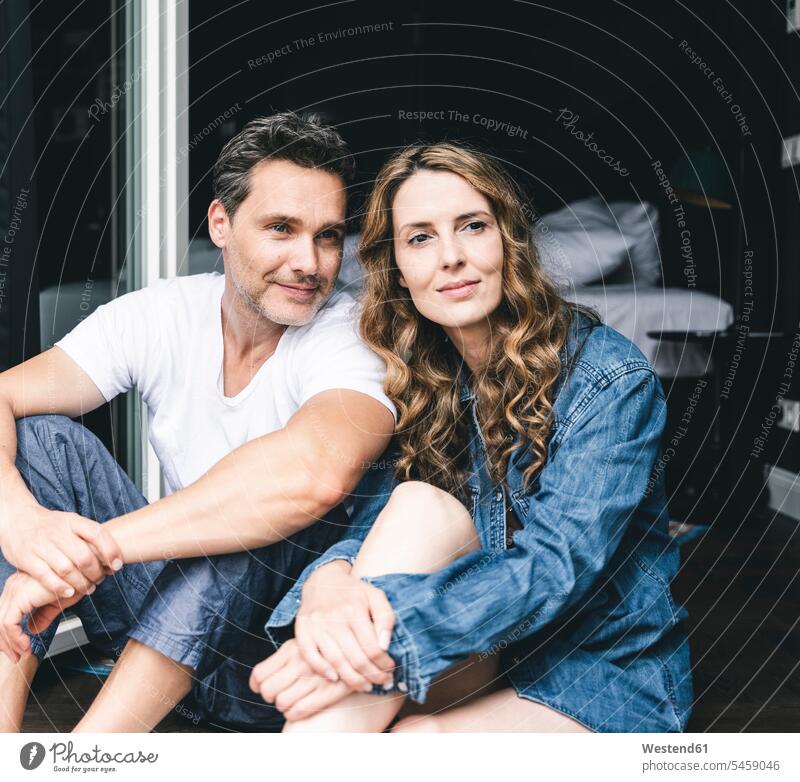 Smiling couple in nightwear at home sitting at French window smiling smile Nightwear happiness happy Seated French Door twosomes partnership couples people