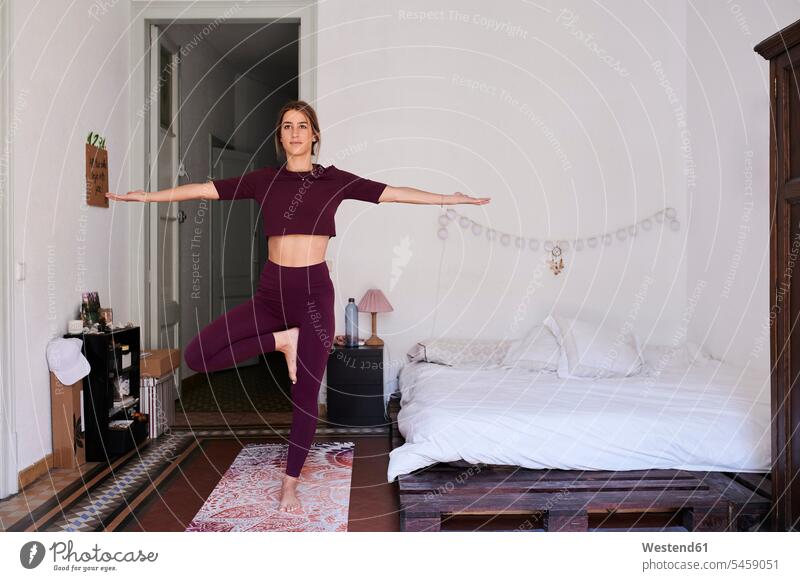 Young brunette woman practising yoga in student dorm Bed - Furniture beds exercise train training smile relax relaxing relaxation delight enjoyment Pleasant