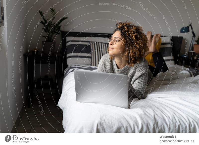 Woman lying on bed, using laptop, surfing the net using a laptop Using Laptops home at home beds laying down lie lying down Surfing the Net Internet