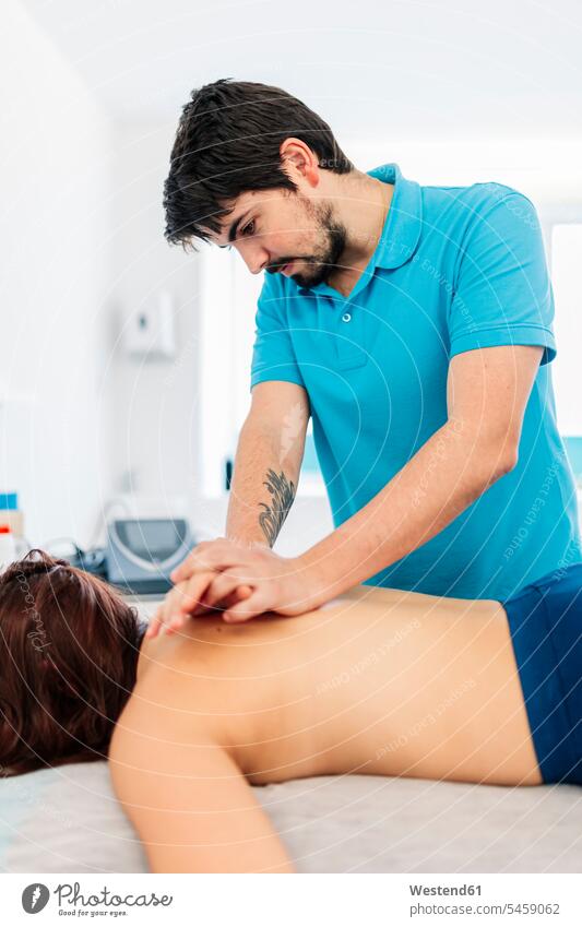 Visually impaired male therapist massaging woman's back in clinic color image colour image indoors indoor shot indoor shots interior interior view Interiors day