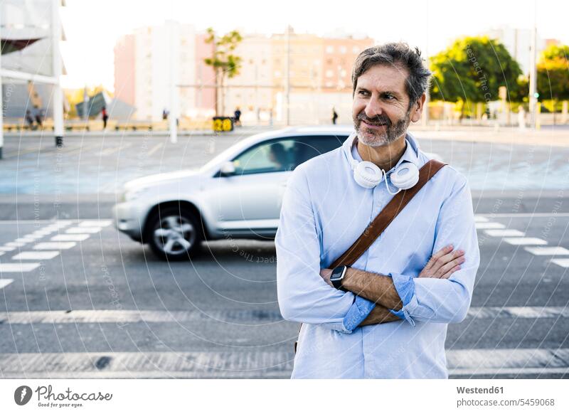 Portrait of smiling mature man with headphones standing at a street road streets roads men males portrait portraits smile headset transportation Adults