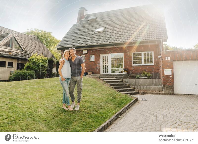 Smiling mature couple embracing in garden of their home smiling smile gardens domestic garden twosomes partnership couples house houses embrace Embracement hug