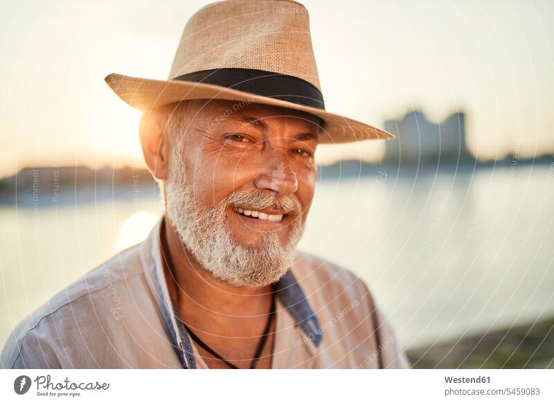 Portrait of a smiling senior man wearing summer hat at the riverside at sunset human human being human beings humans person persons caucasian appearance