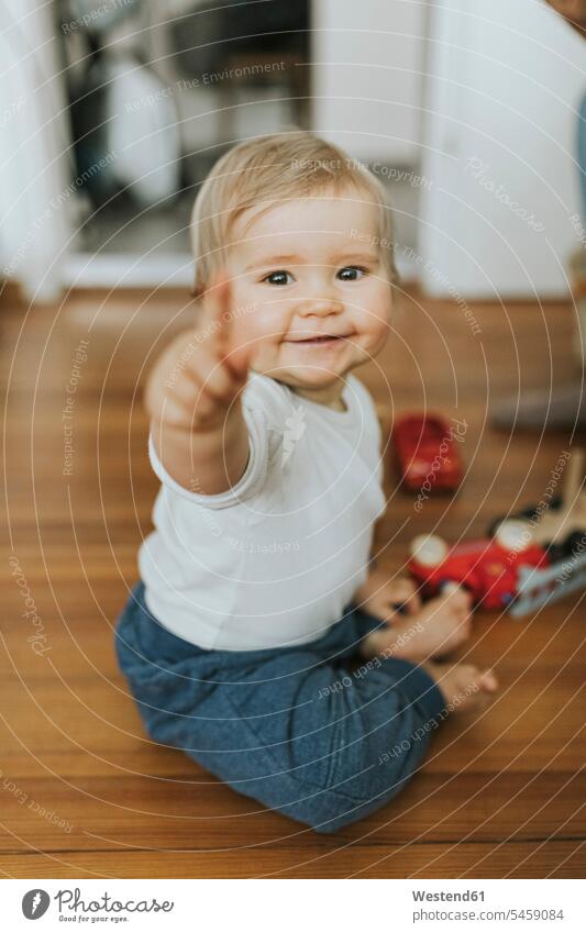 Smiling baby girl pointing finger at home toys smile Seated sit play relax relaxing relaxation delight enjoyment Pleasant pleasure Cheerfulness exhilaration