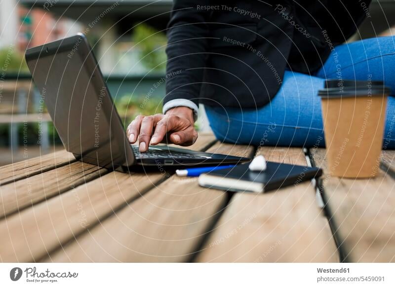 Businesswoman sitting on table outdoors using laptop, partial view businesswoman businesswomen business woman business women Table Tables Laptop Computers