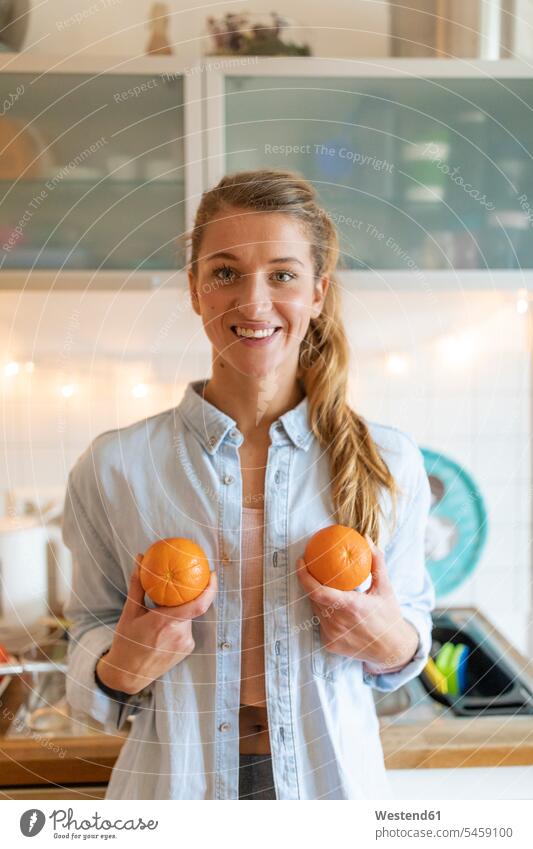 Portrait of happy young woman holding oranges at home human human being human beings humans person persons celibate celibates singles solitary people