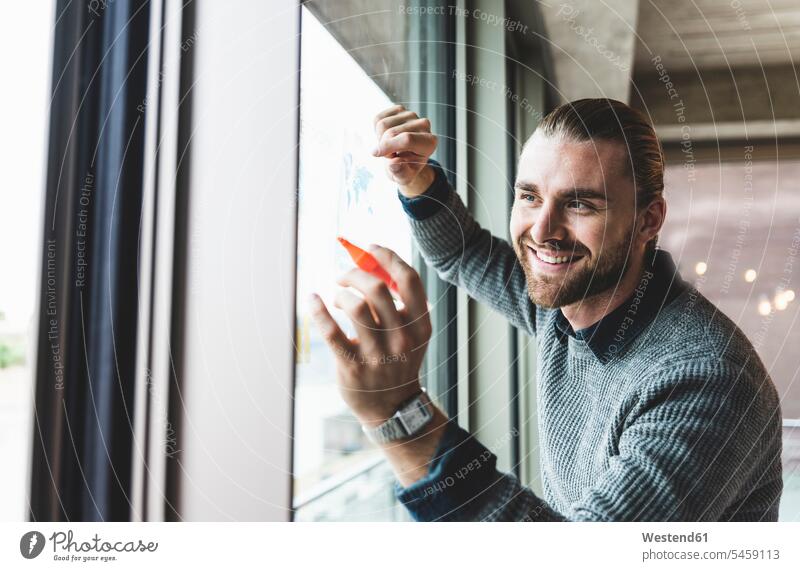 Smiling young businessman working on data at windowpane windows Businessman Business man Businessmen Business men smiling smile At Work business people
