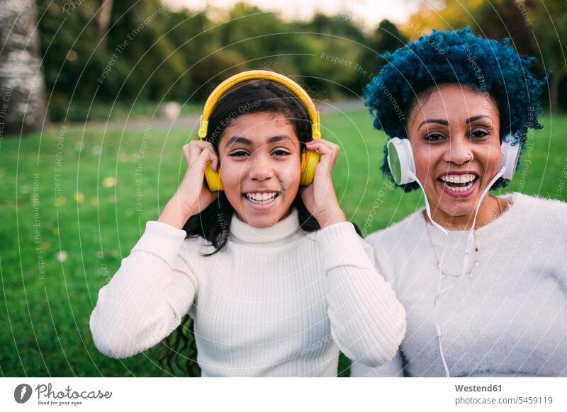 Happy mother and daughter listening music through headphones in park color image colour image Portugal leisure activity leisure activities free time