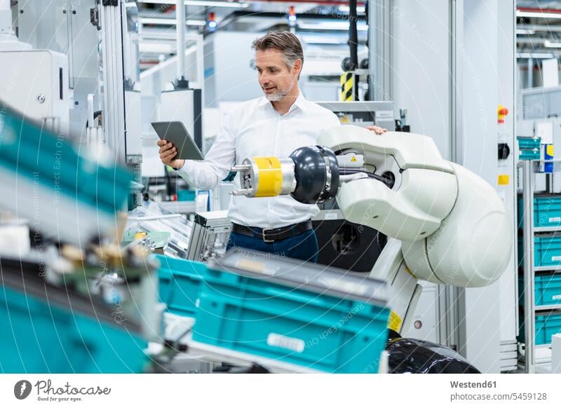 Businessman with tablet at assembly robot in a factory Occupation Work job jobs profession professional occupation business life business world business person