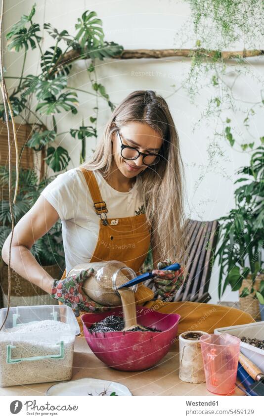 Young woman working at table in a small gardening shop Occupation Work job jobs profession professional occupation flower pot flower pots flowerpots Tables