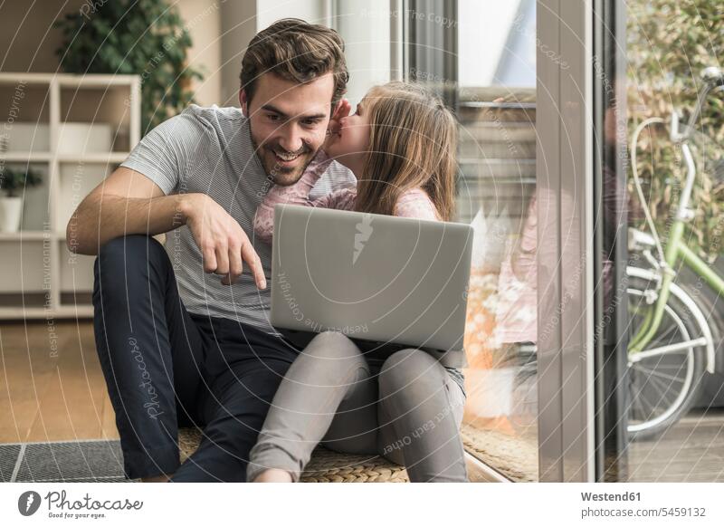Young man and little girl surfing the net together Surfing the Net sitting Seated sitting on ground Sitting On The Floor Sitting On Floor shelf Shelve rack