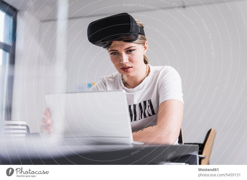 Young woman with laptop and VR glasses working at desk in office specs Eye Glasses spectacles Eyeglasses females women At Work virtual offices office room