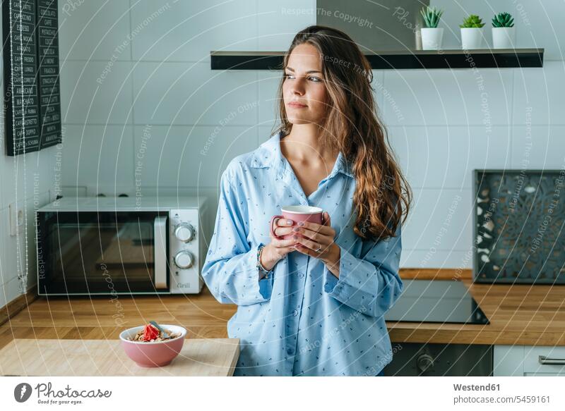Portrait of young woman wearing pyjama in kitchen at home holding cup of coffee human human being human beings humans person persons caucasian appearance