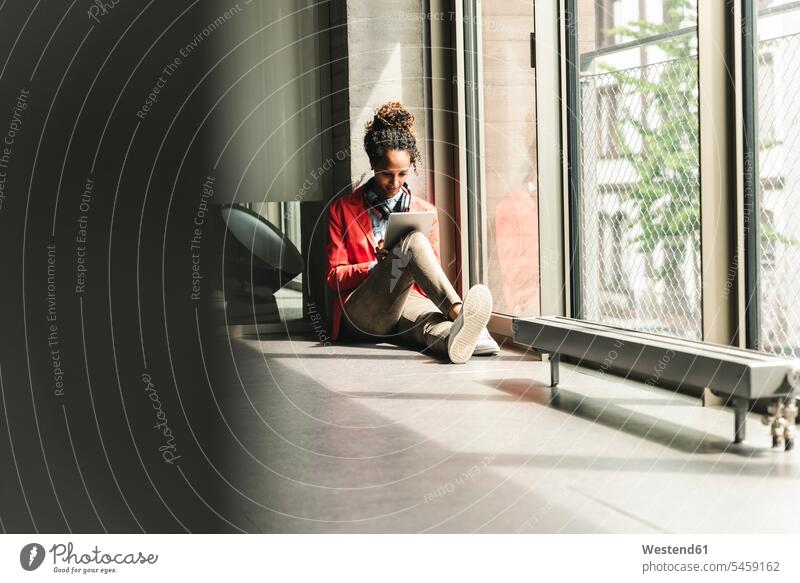 Young woman with headphones sitting on floor, using digital tablet creative professional Creative People creatives Creative Occupation creative professionals