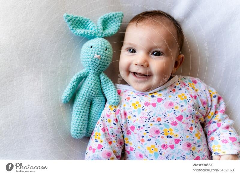 Baby girl with a bunny toy lying on bed human human being human beings humans person persons babies infant infants nurseling nurselings 2 to 5 months