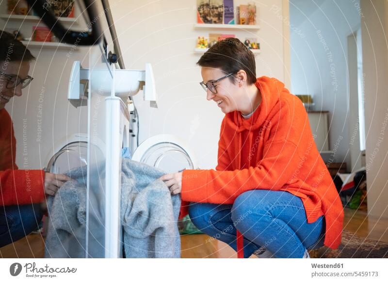Young woman doing the laundry at home Laundry young women young woman chores kitchen domestic kitchen kitchens Washing Machine Washing Machines Washer Washers